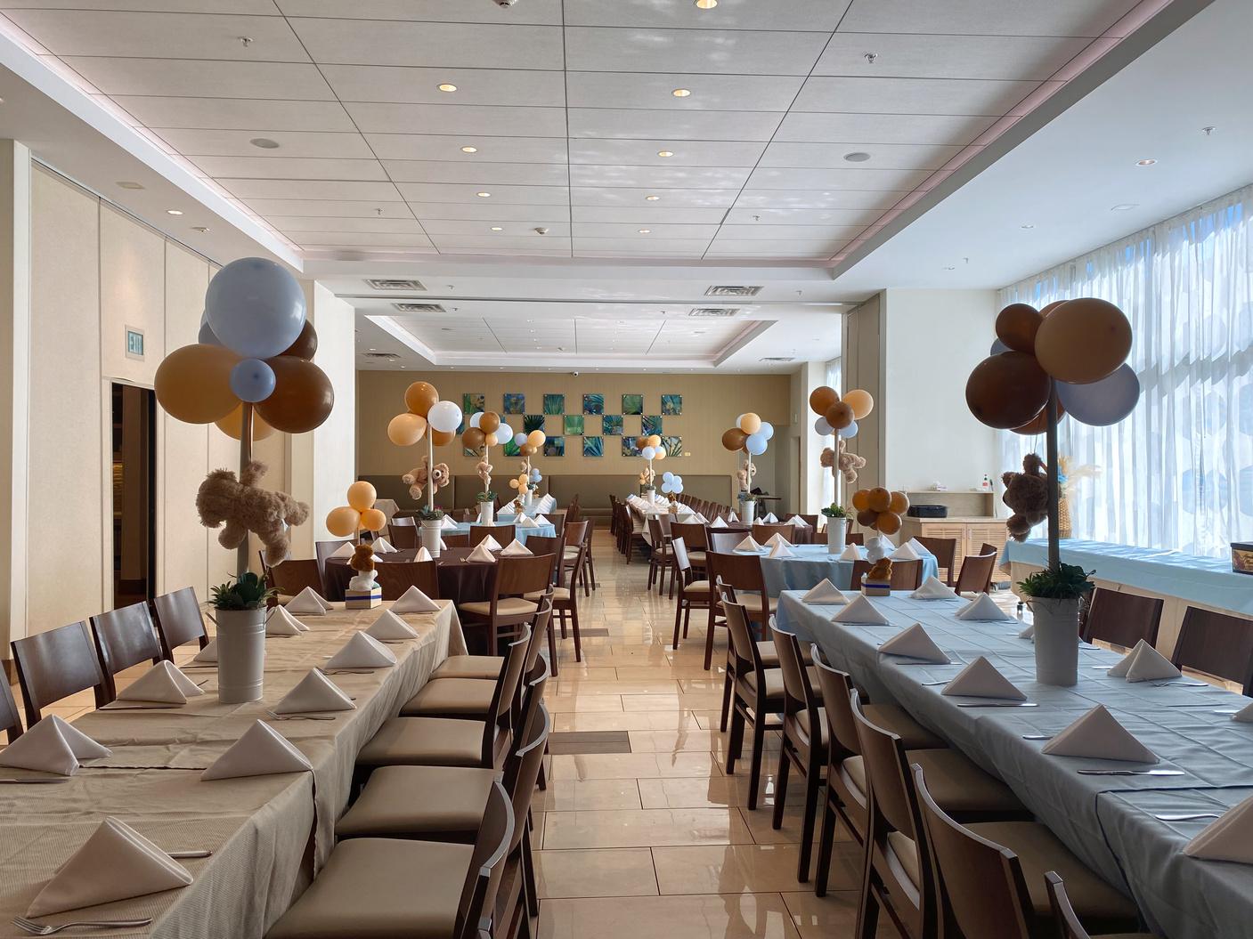 An event space with long banquet tables, wood chairs, neutral balloons, and floor-to-ceiling windows at Hyatt House at Anaheim Resort/Conv Cntr.