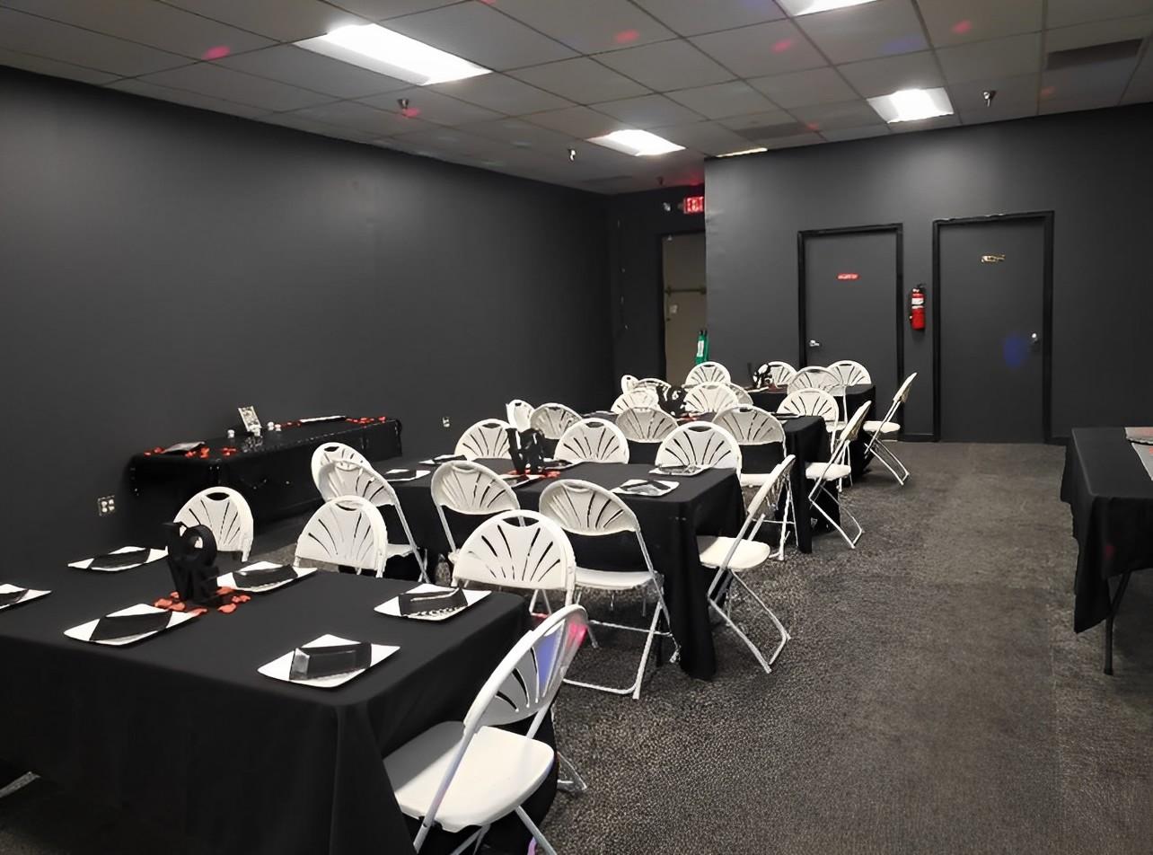 An event venue with folding white chairs and tables covered with black linens and matching napkins at MJC Tag and Title LLC.