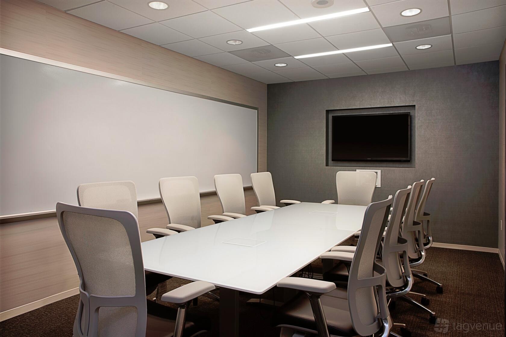 A meeting room with a long white conference table, ergonomic chairs, wall-mounted whiteboard, and flat-screen TV at AdvantEdge Chevy Chase.