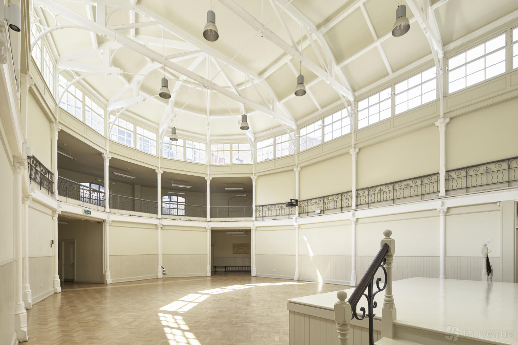 A spacious hall with high vaulted ceilings, arched windows, and a raised stage at Shoreditch Tab Centre.