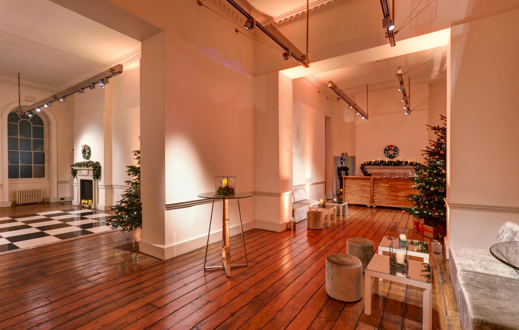 An event venue with polished wooden floors, white walls, and festive decor at Somerset House.