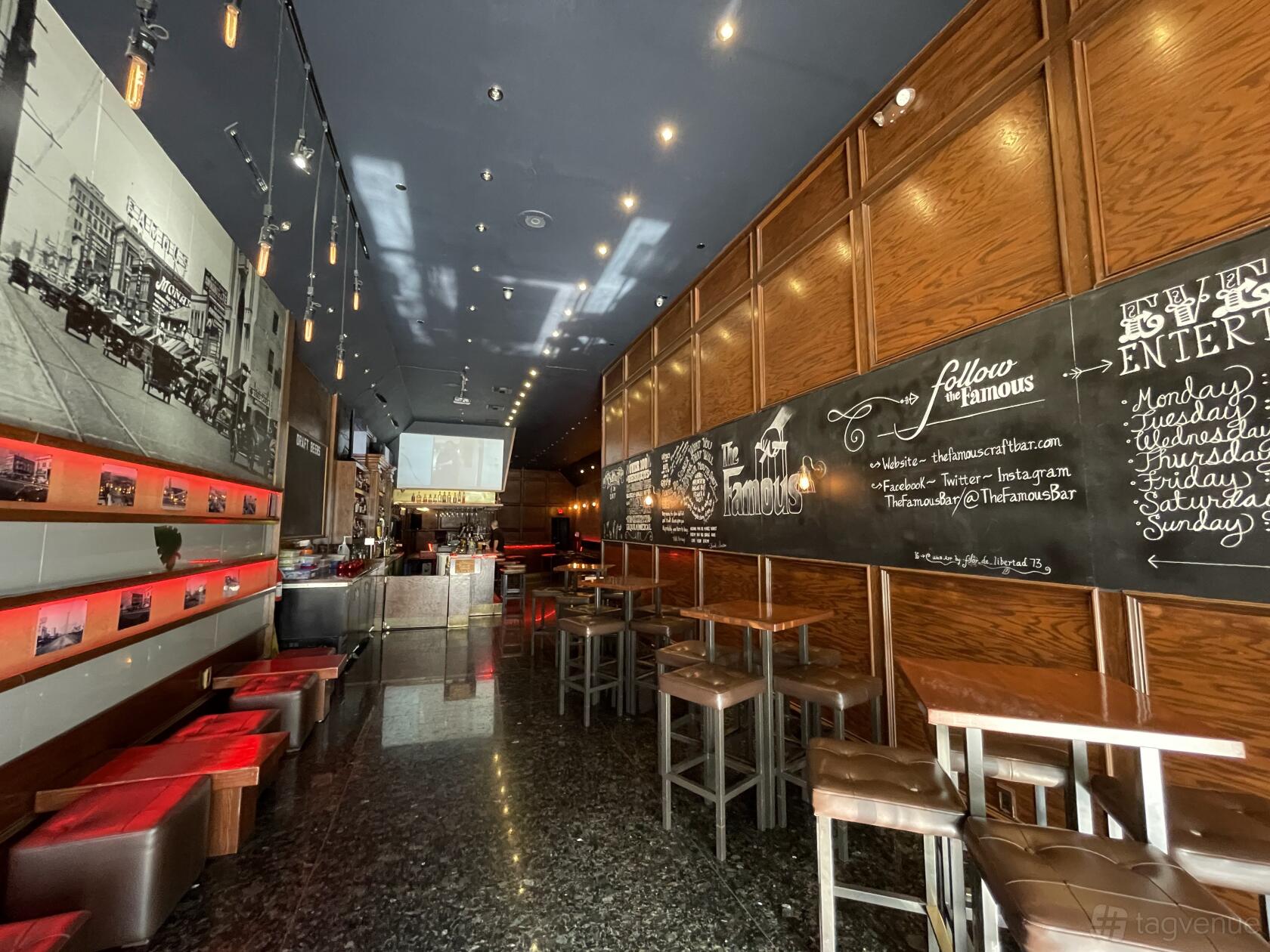A bar with high-top tables, blackboard menus, wood-paneled walls, and vintage photos at The Famous.
