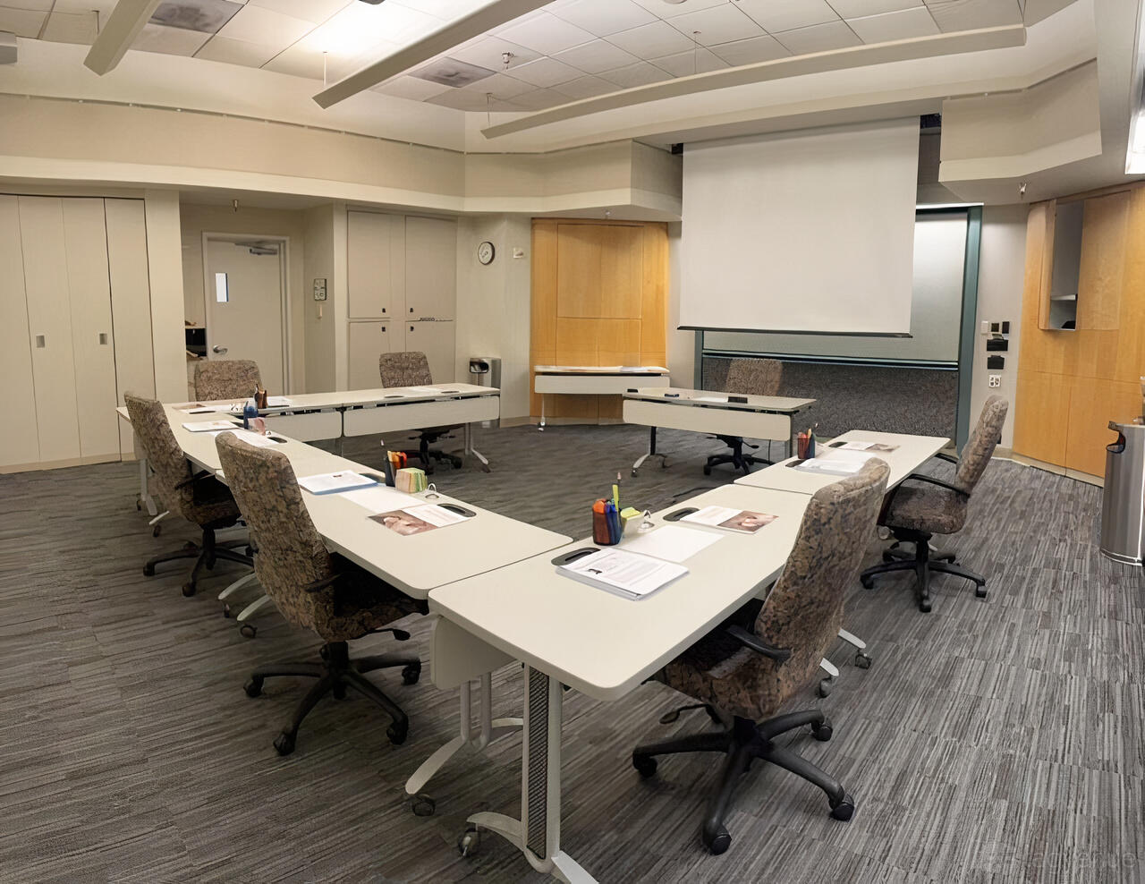 A meeting room with U-shaped tables, rolling office chairs, and a ceiling-mounted projector at AMA's SF Executive Conference Center.