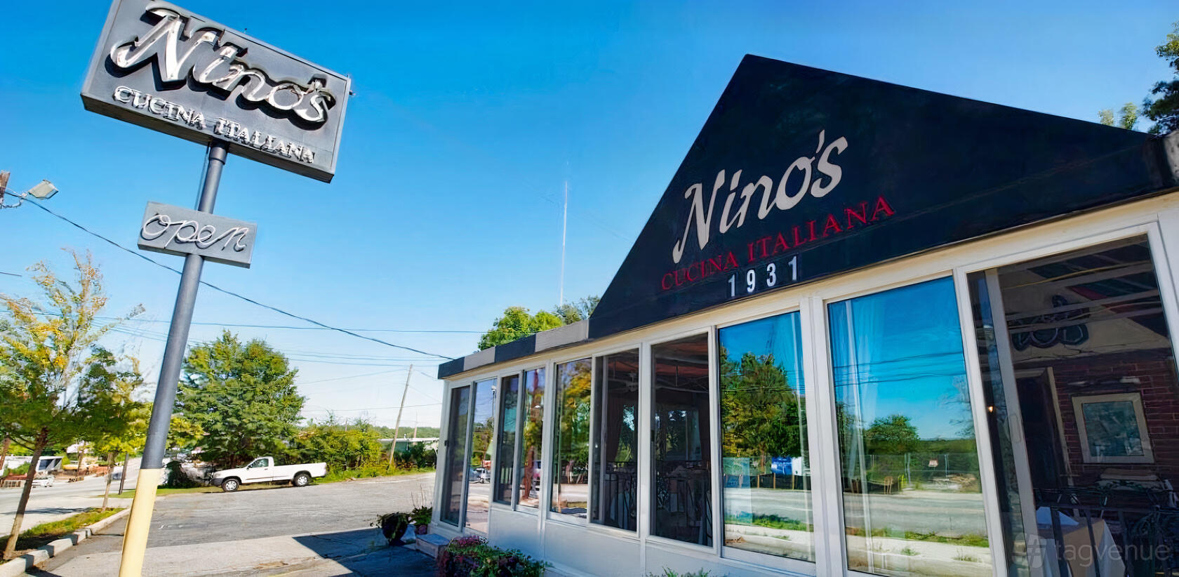 A restaurant exterior with floor-to-ceiling windows, black awning, and visible signage at Nino's Italian Restaurant.