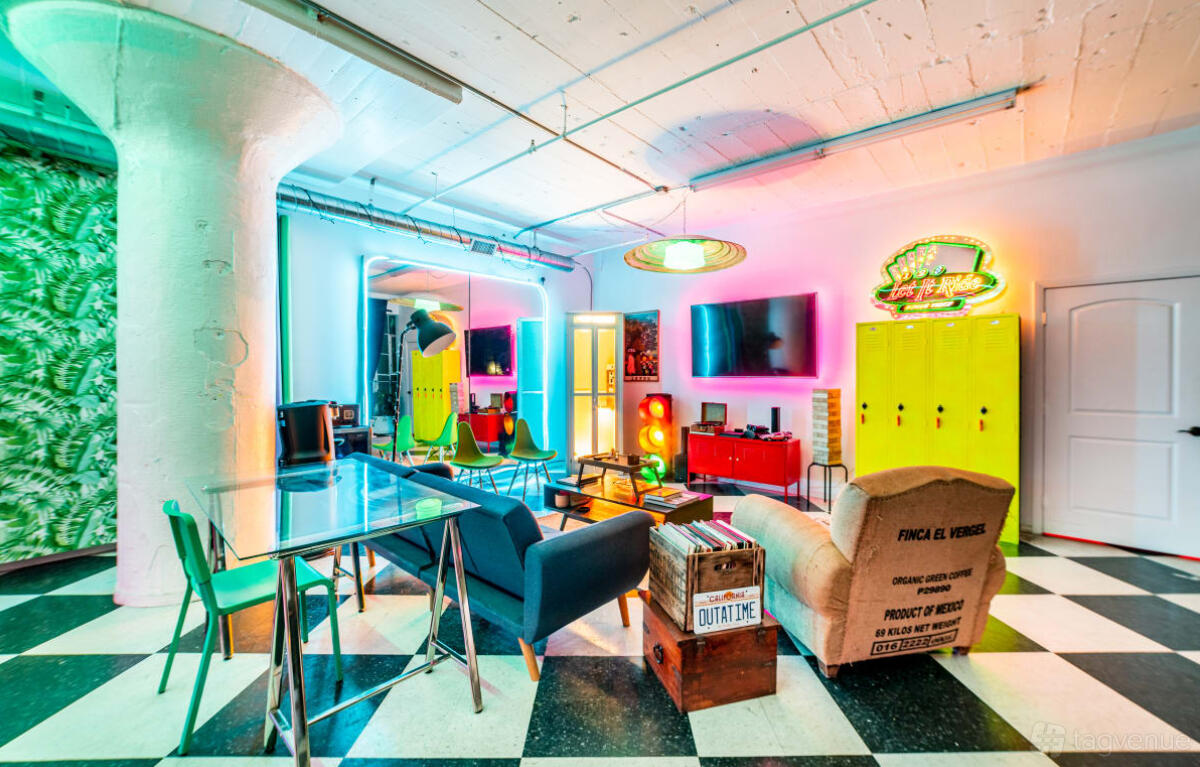 An event venue with retro neon lights, vibrant decor, checkered flooring, and vintage seating at Drip Studios.