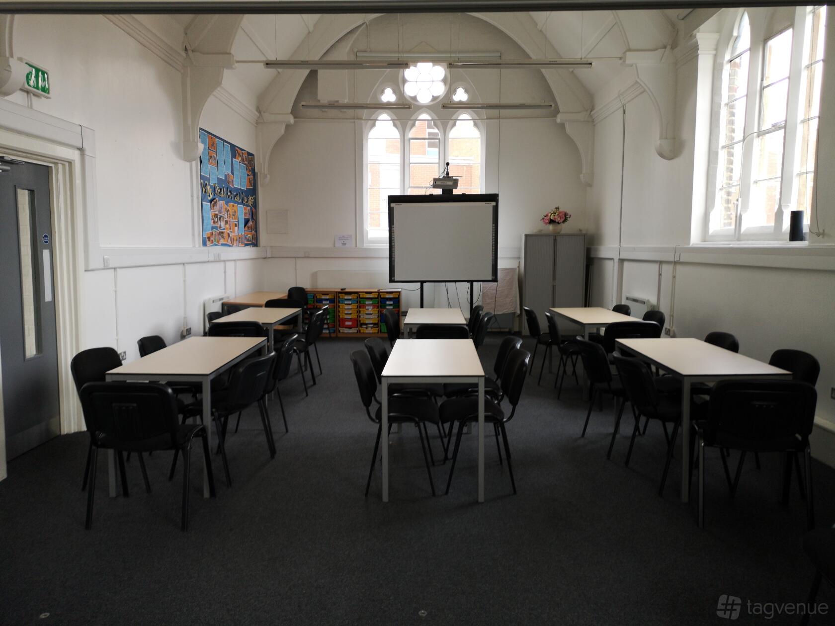 An event venue with high arched ceilings, rectangular tables, and classroom chairs at Teaching London: LDBS SCITT.