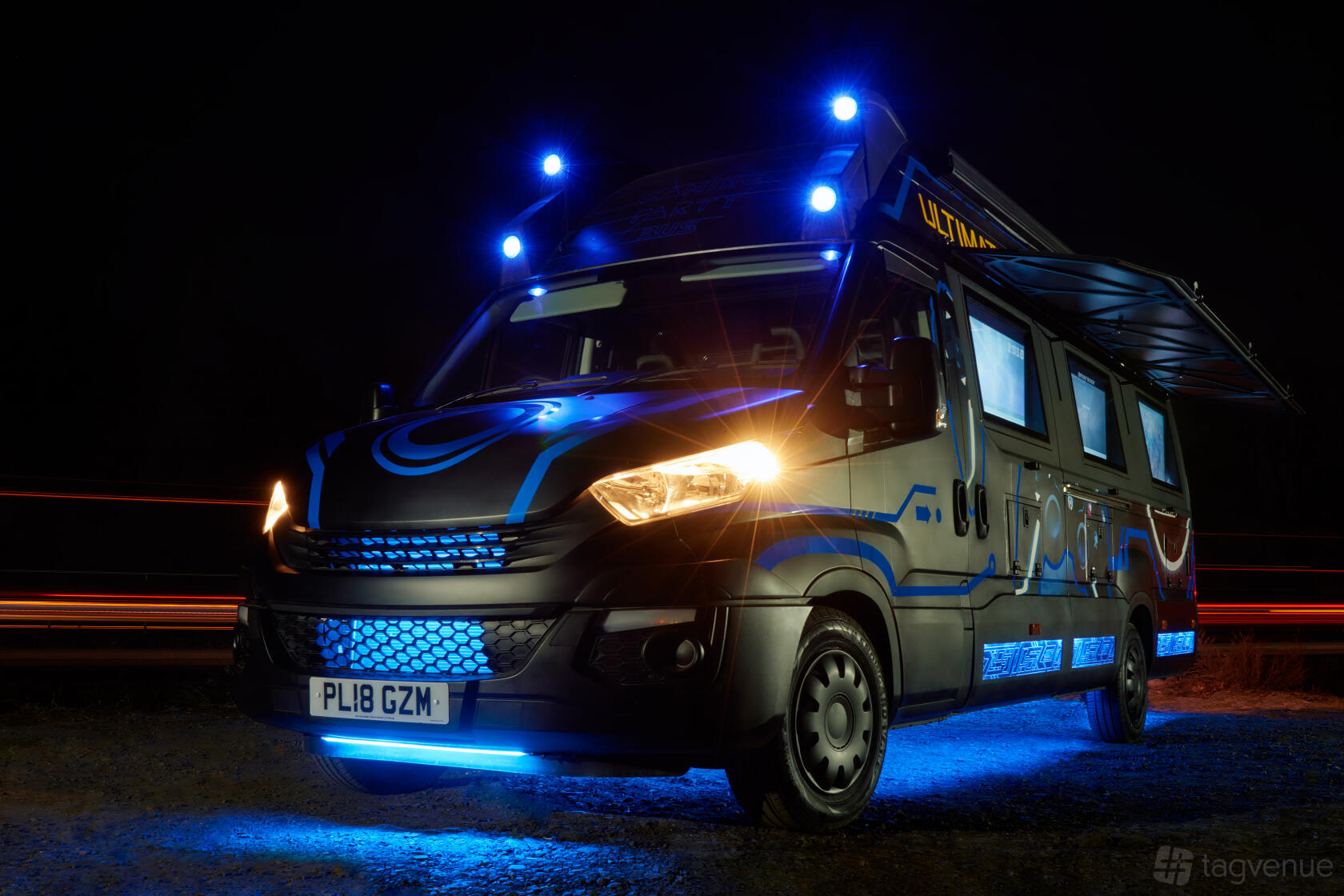 A party bus with neon blue exterior lights and an extended awning at Gaming Party Bus.