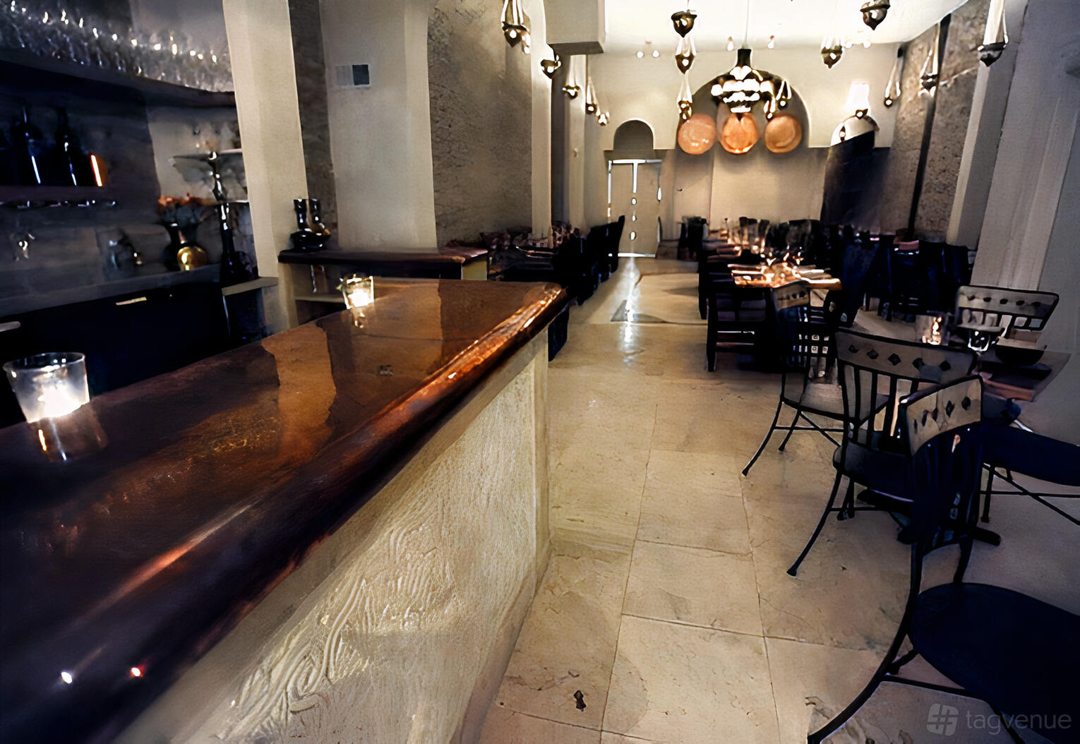 An event space in a restaurant with warm pendant lighting, wooden tables, and a polished bar at Taxim.