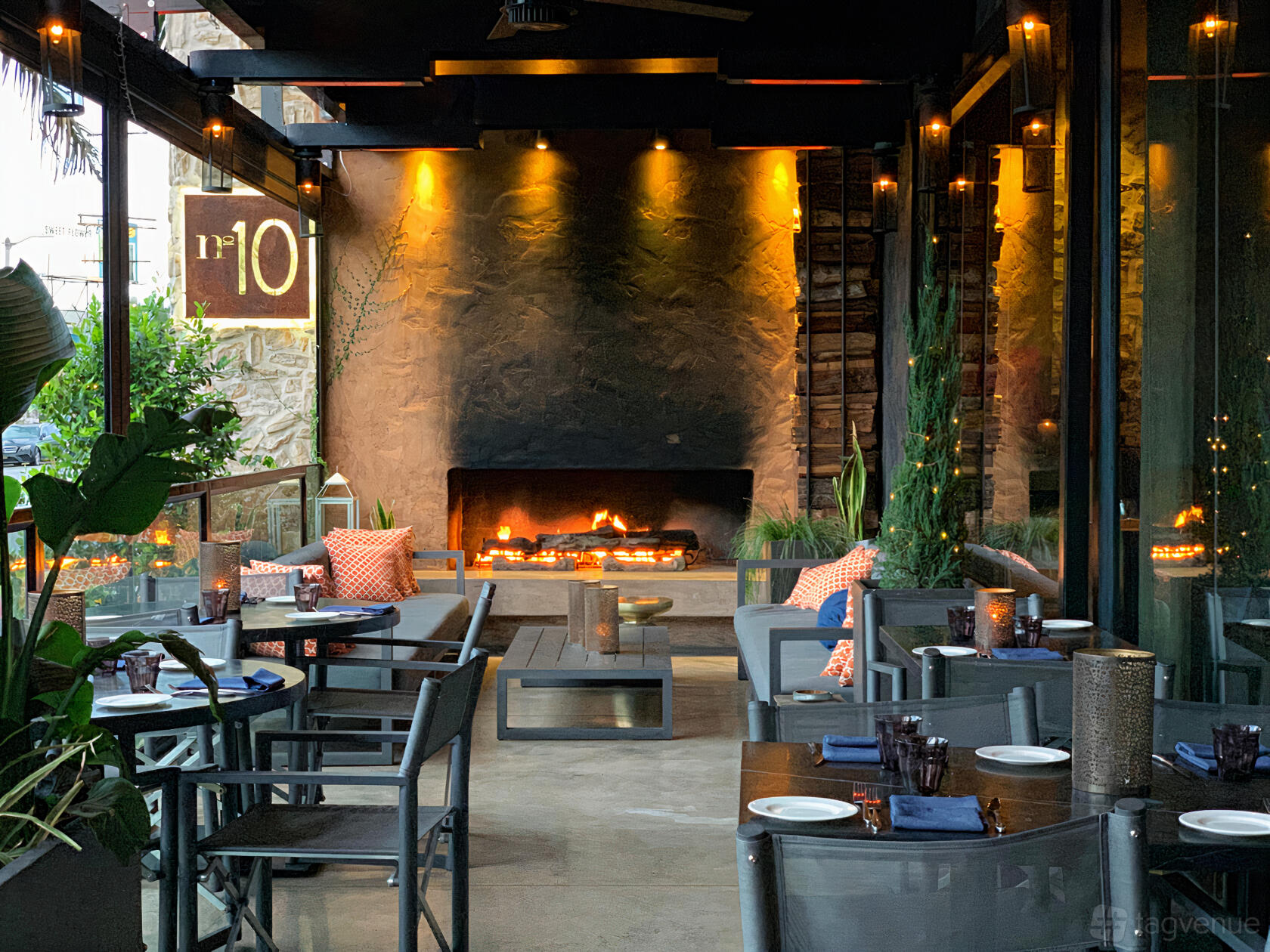 An outdoor restaurant patio with a fireplace, string lights, and cushioned seating at N10 Restaurant.