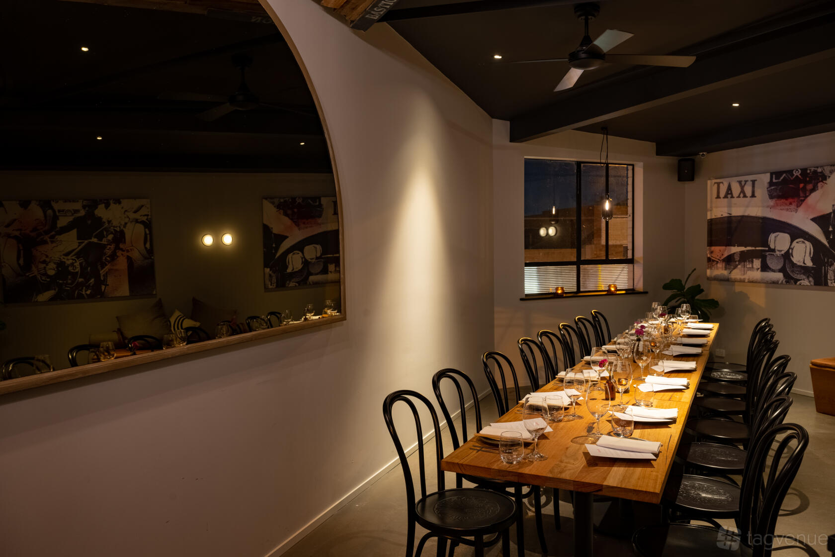 A dining room with a long wooden table, black chairs, minimal decor, and warm lighting at Luxsmith.