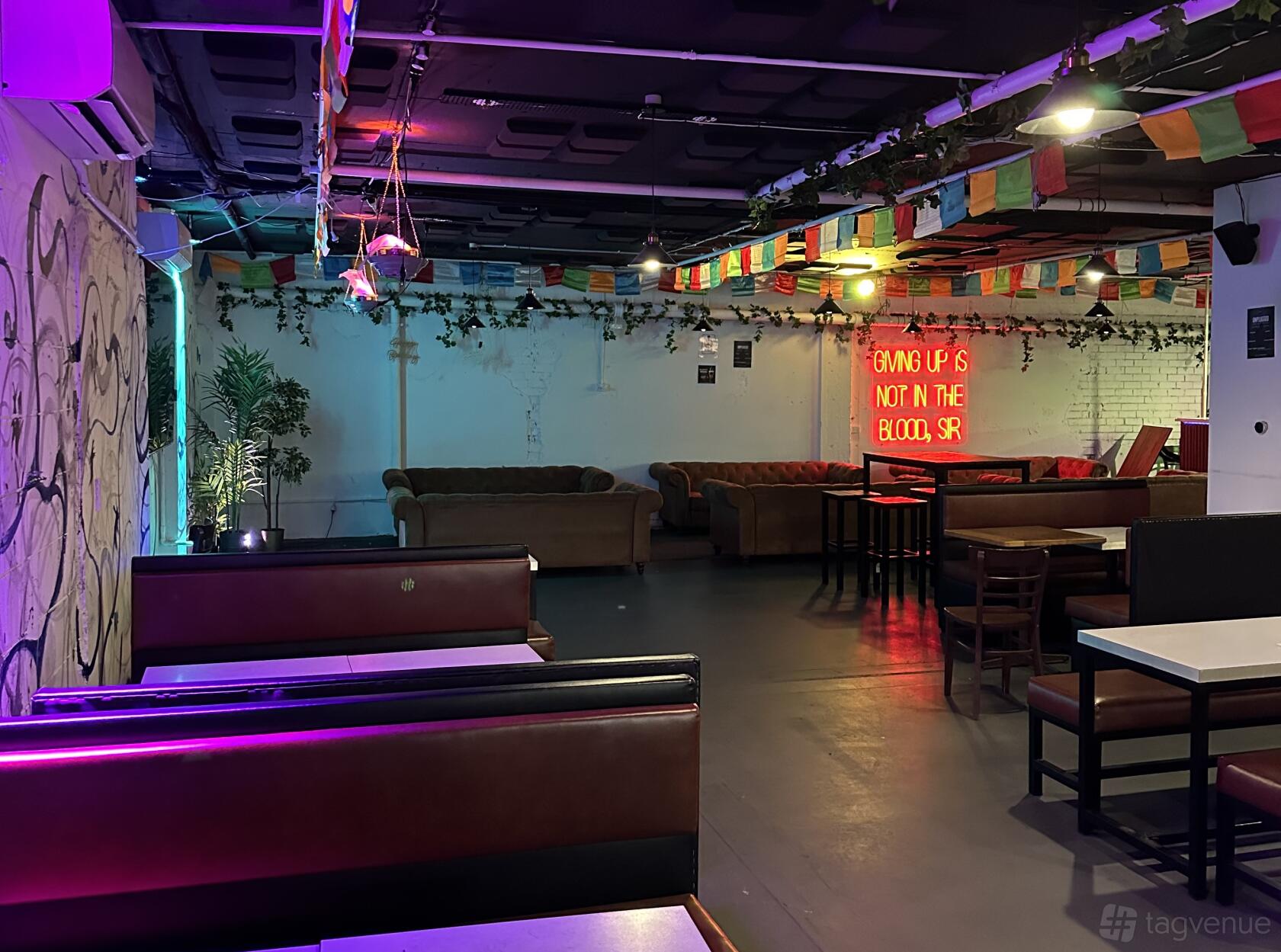 A restaurant with colorful pennant flags, red booths, leather sofas, and a neon sign at Roxy Kitchen and Bar.