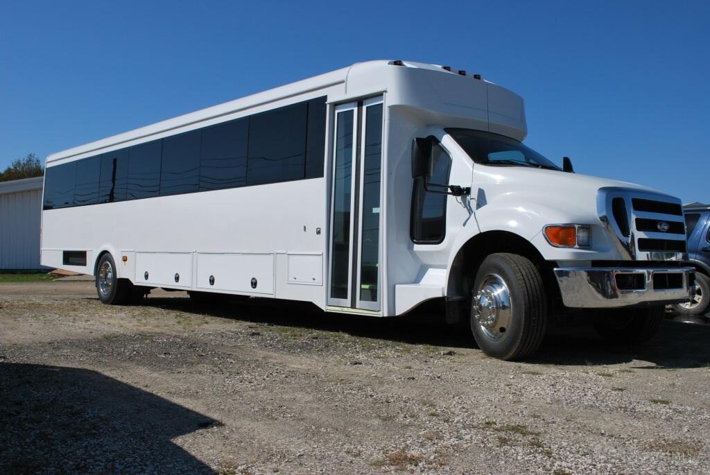 A white party bus with tinted windows and chrome accents parked outdoors at US Bargain Limo.