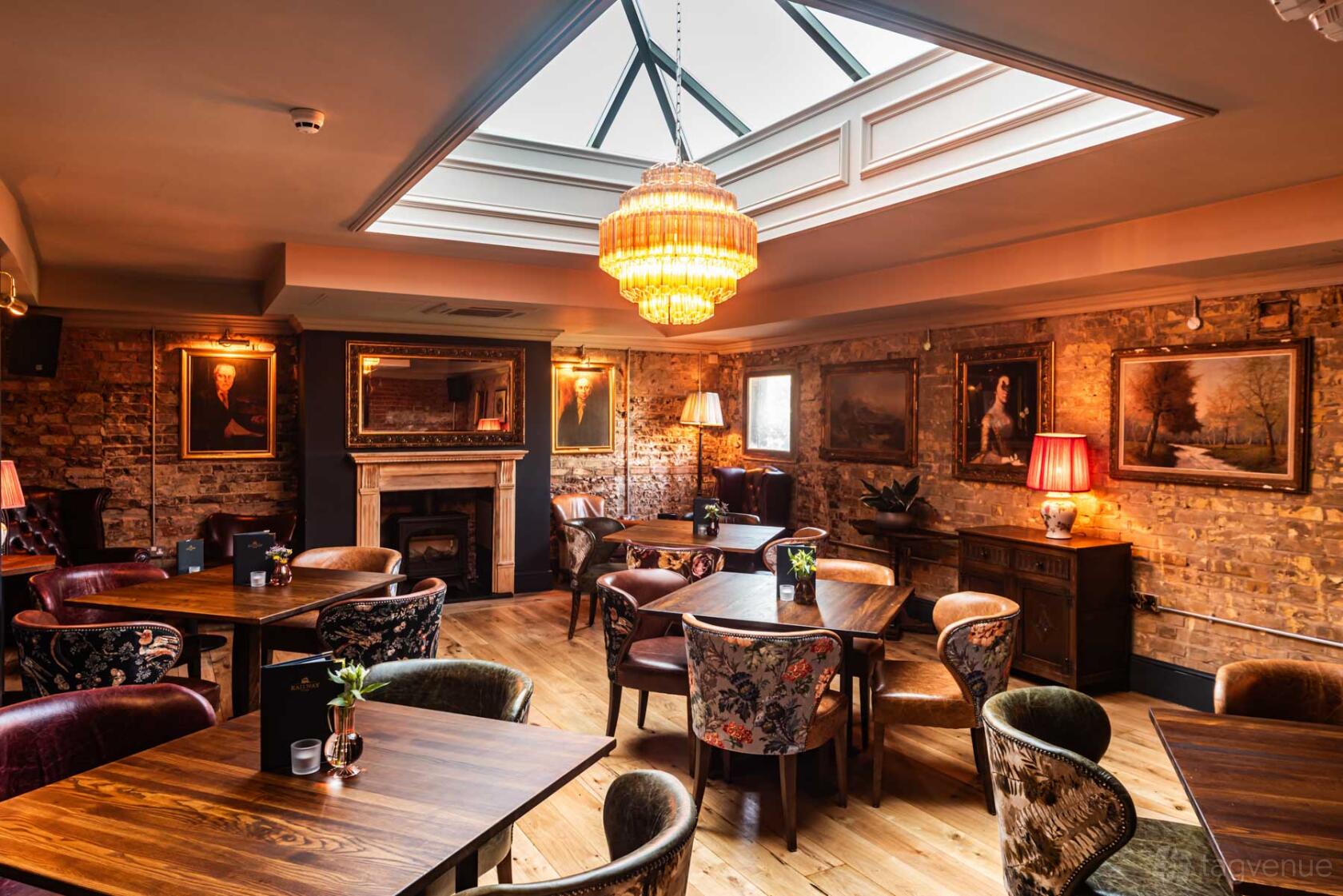An event space in a pub with exposed brick walls, vintage armchairs, and a large skylight at The Railway.