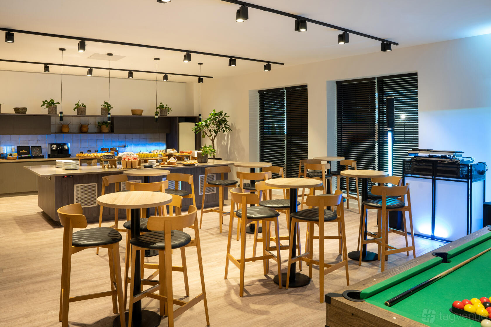 A hotel cafe with wooden high-top tables, barstools, a buffet counter, and a pool table at INNSiDE by Melia Liverpool.