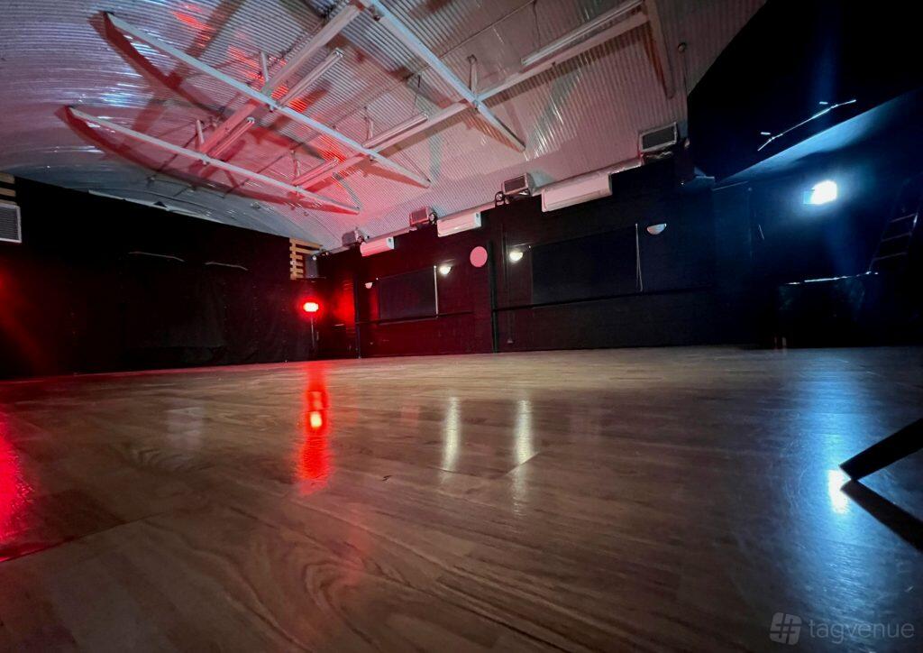 A dance studio with wood flooring, exposed beams, and dramatic red and blue lighting at Studio 68 London.