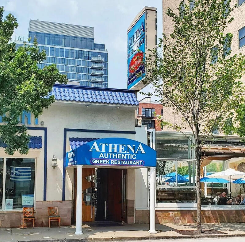 A restaurant exterior with a blue awning, white facade, and street trees at Athena Greek Restaurant.