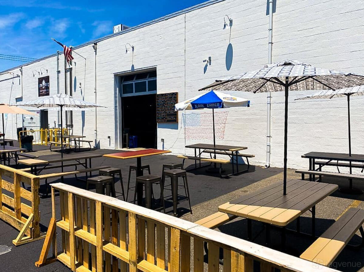 An outdoor beer garden with picnic tables, umbrellas, and wooden fencing at South Shore Craft Brewery.