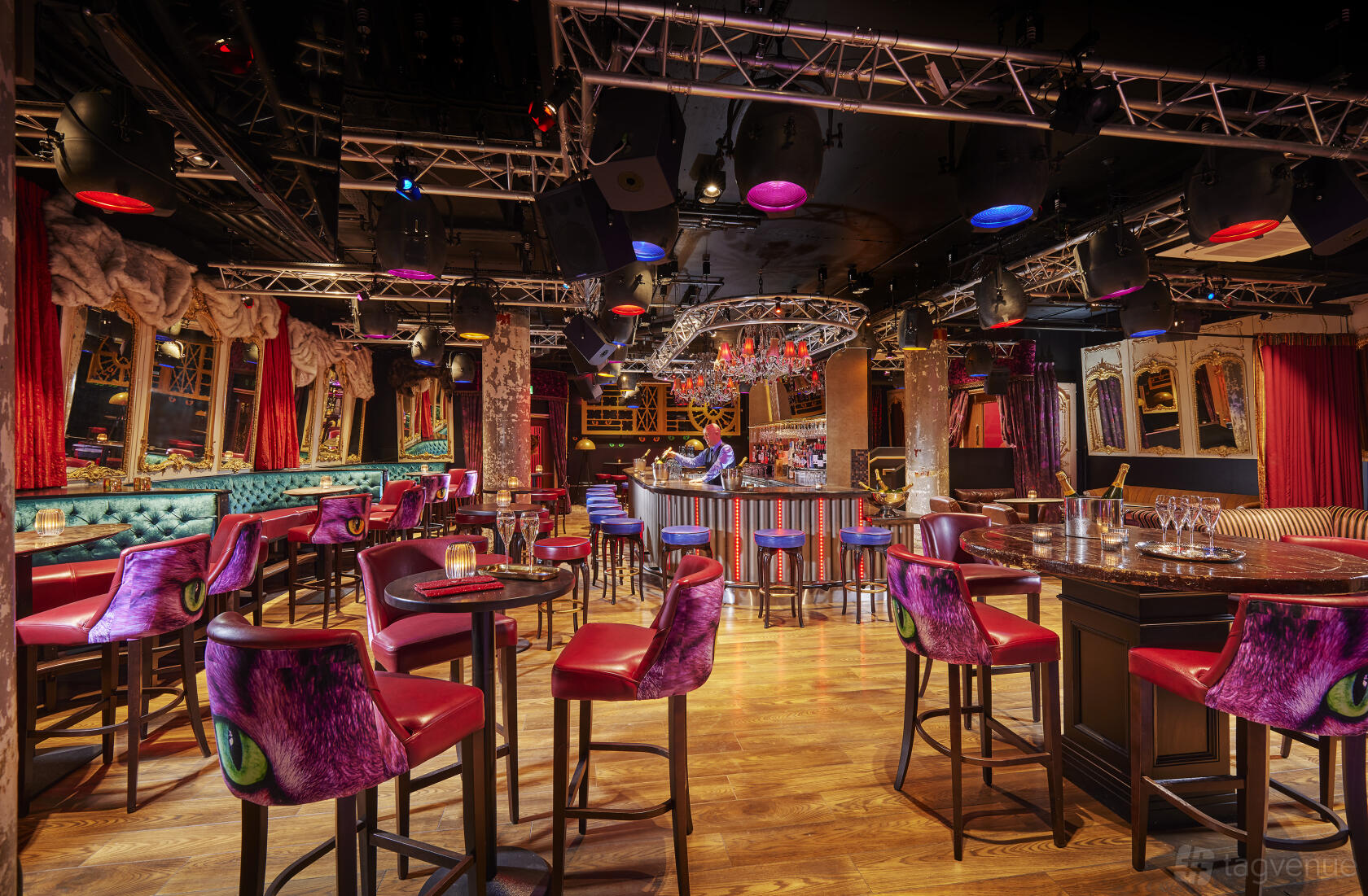 A restaurant lounge with tufted teal banquettes, purple velvet chairs, chandeliers, and gold-framed mirrors at Bartley's Bar and Restaurant.