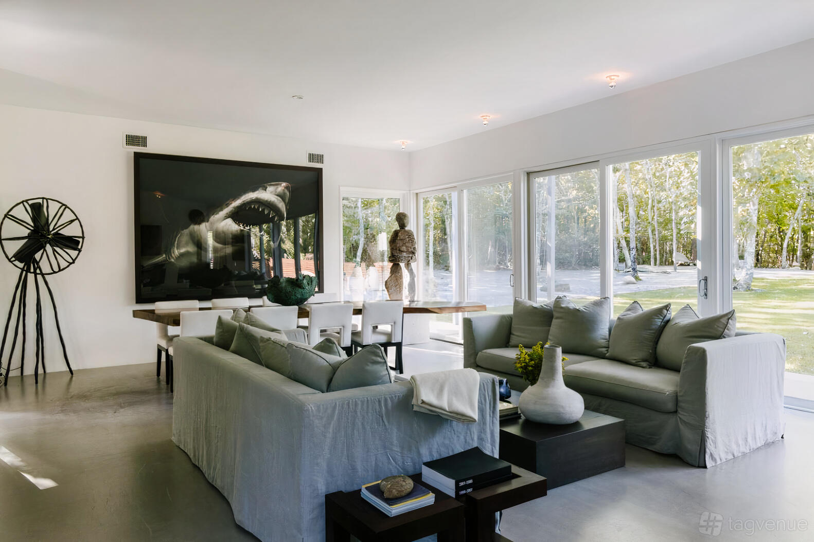 A country house with floor-to-ceiling windows, neutral sofas, and a large wall art piece at Casa Eximia.