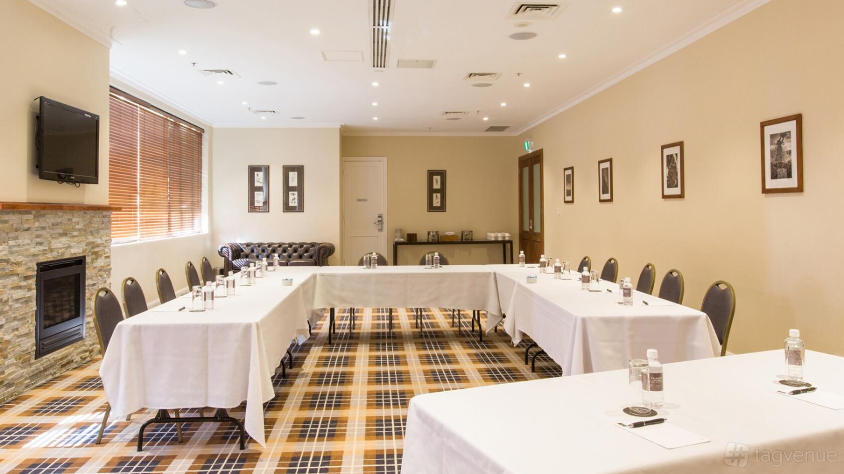 An event space with U-shaped tables, tartan carpet, and bottled water at Fairmont Resort Blue Mountains.