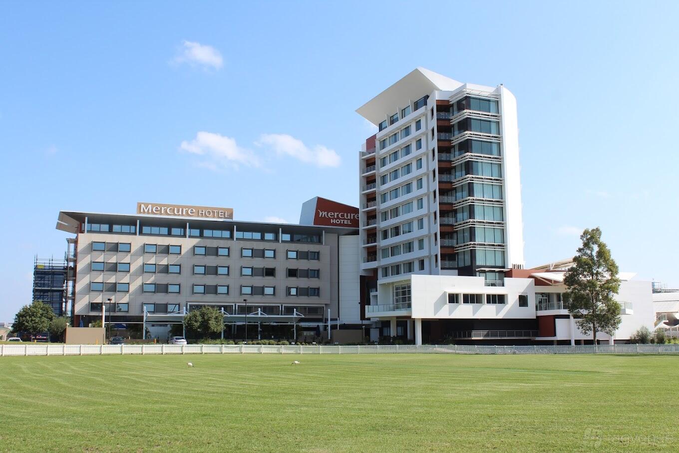 A versatile event space with a multi-story building featuring large windows and adjacent open field at LCC Venues.