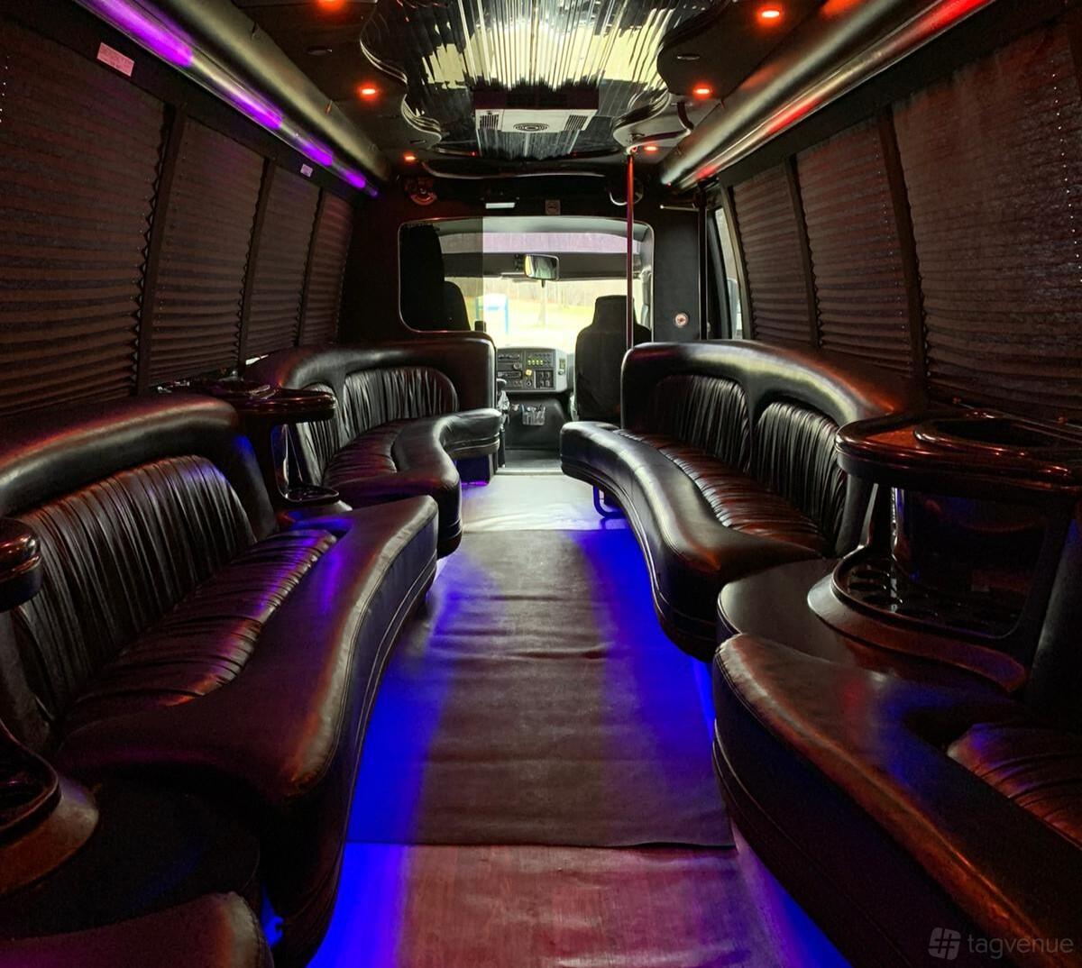 A party bus with black leather wraparound seating, cup holders, and floor lighting at KVM Limousine Services.