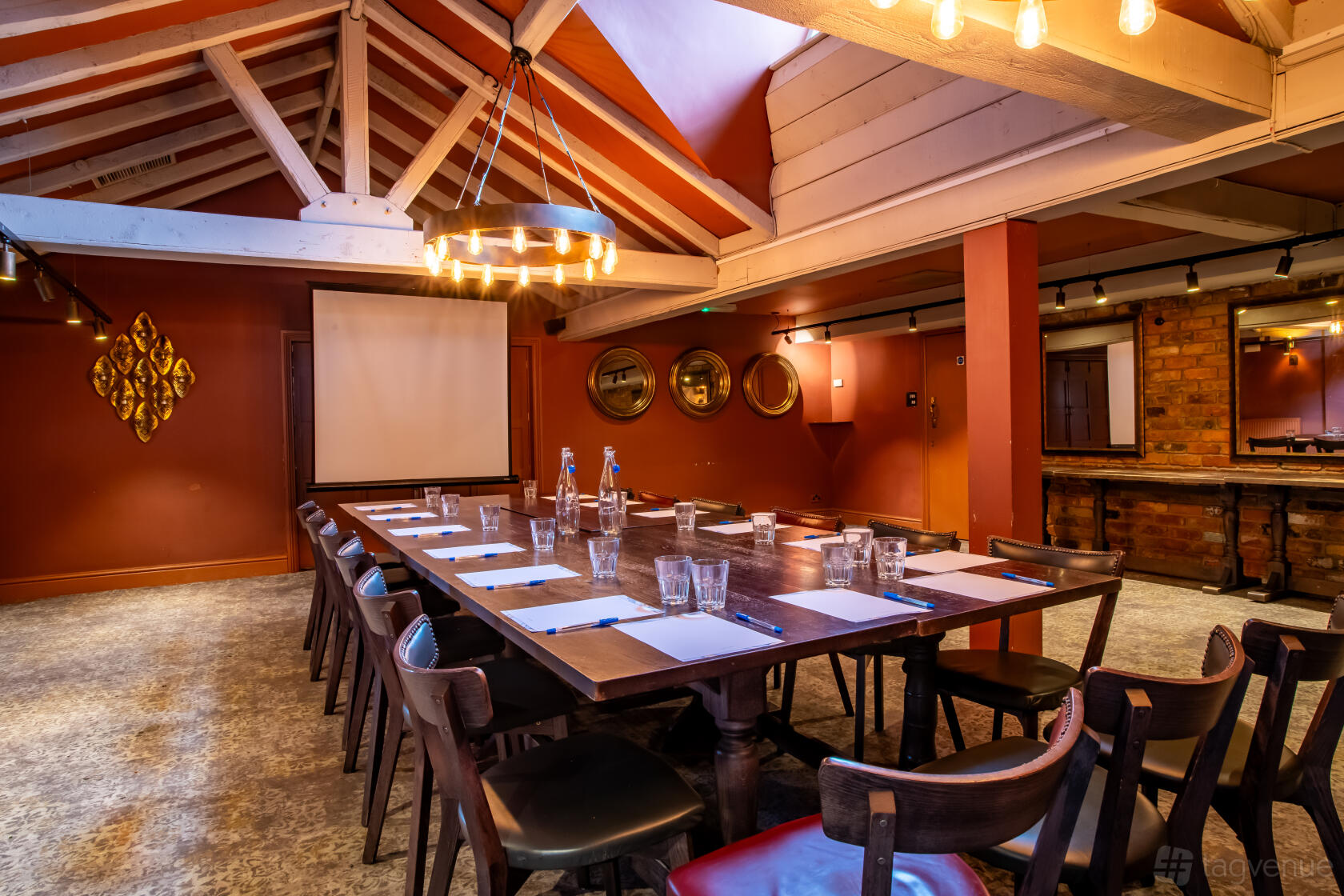 An event space in a pub with exposed beams, a chandelier, and a long meeting table at Bell Bellbroughton.