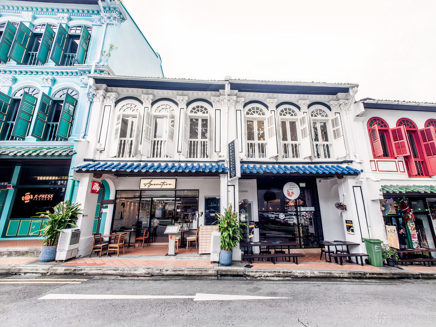 A shophouse-style versatile event space with arched windows, white facade, and blue tiled roof at The Secret Patio.