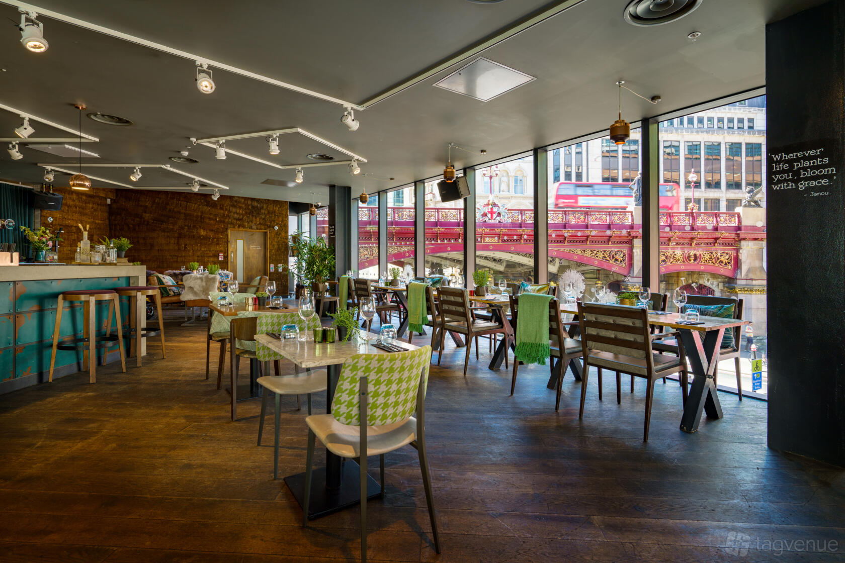 An event space in a restaurant with floor-to-ceiling windows, wooden tables, and city views at The Fable.