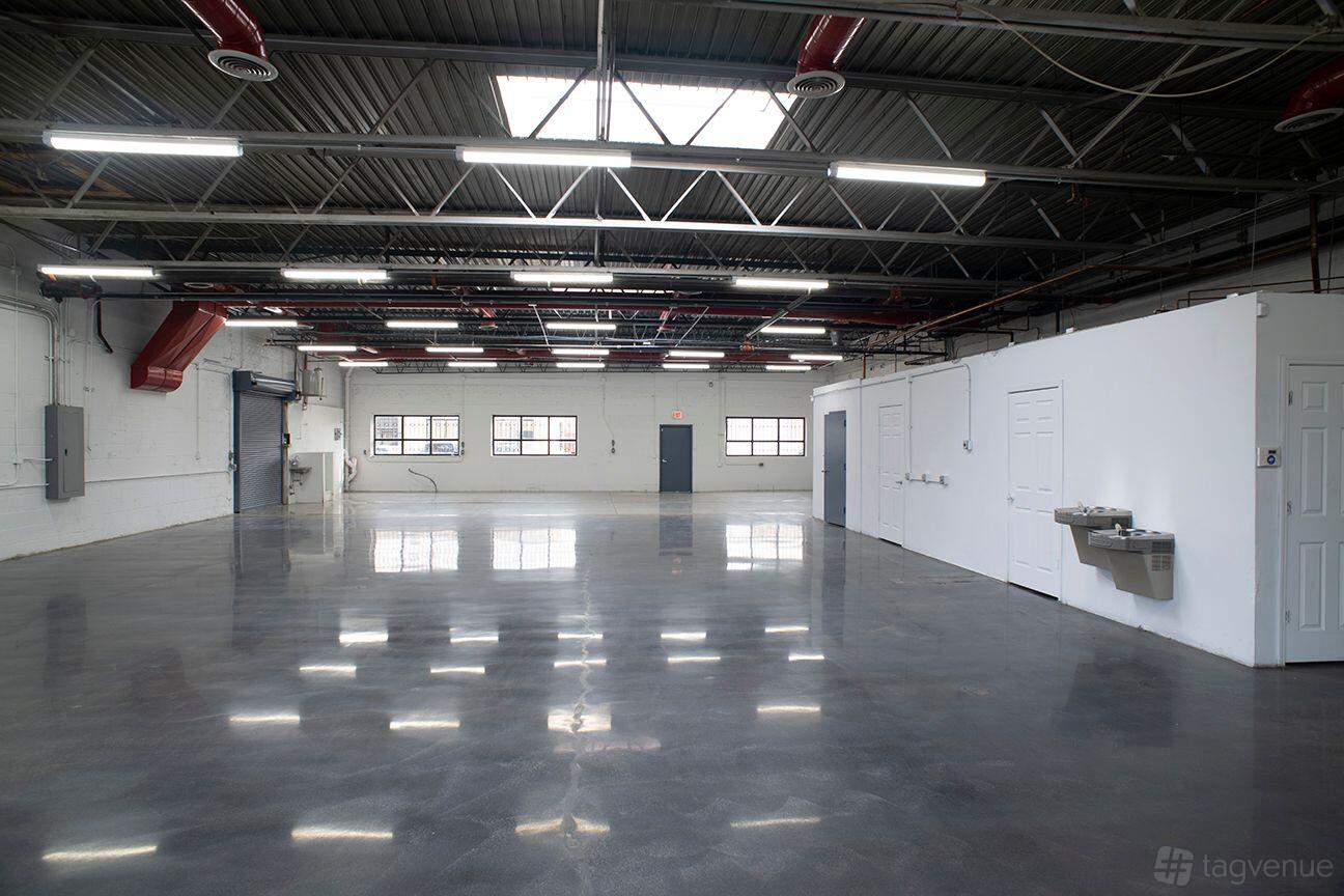 A warehouse with polished concrete floors, white walls, exposed ceiling beams, and skylights at 3300 N Knox.
