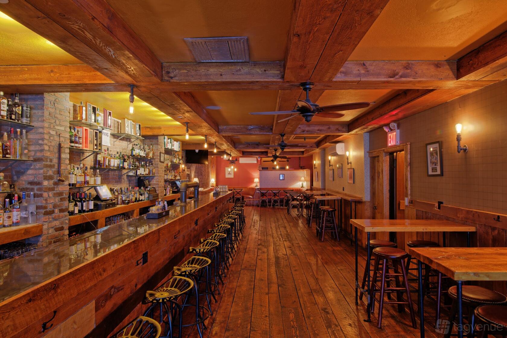 A cocktail bar with exposed brick walls, wood beams, and a long bar counter at Monk McGinn's.