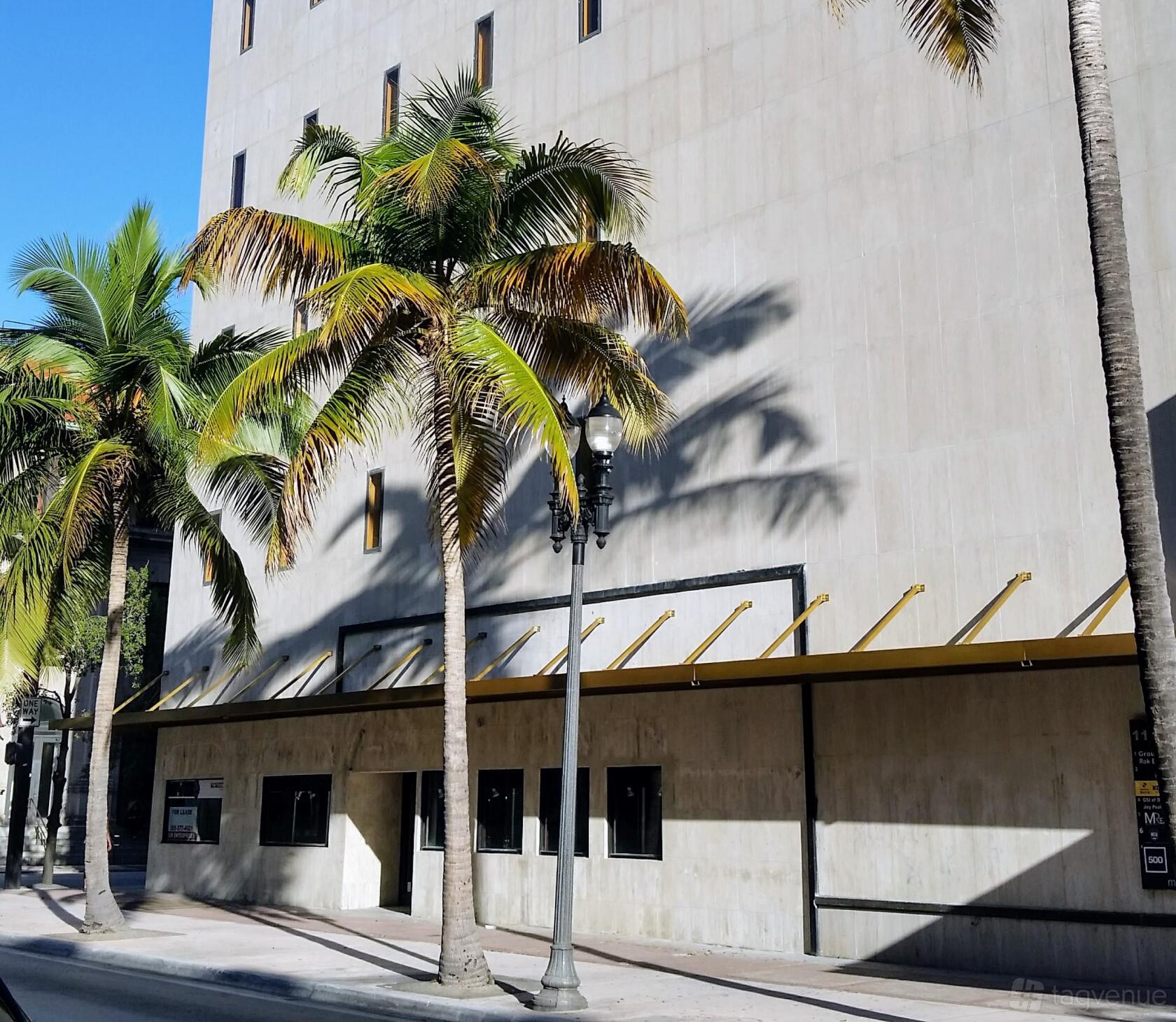 A versatile event space with a minimalist facade, large windows, and palm trees at mindwarehouse.