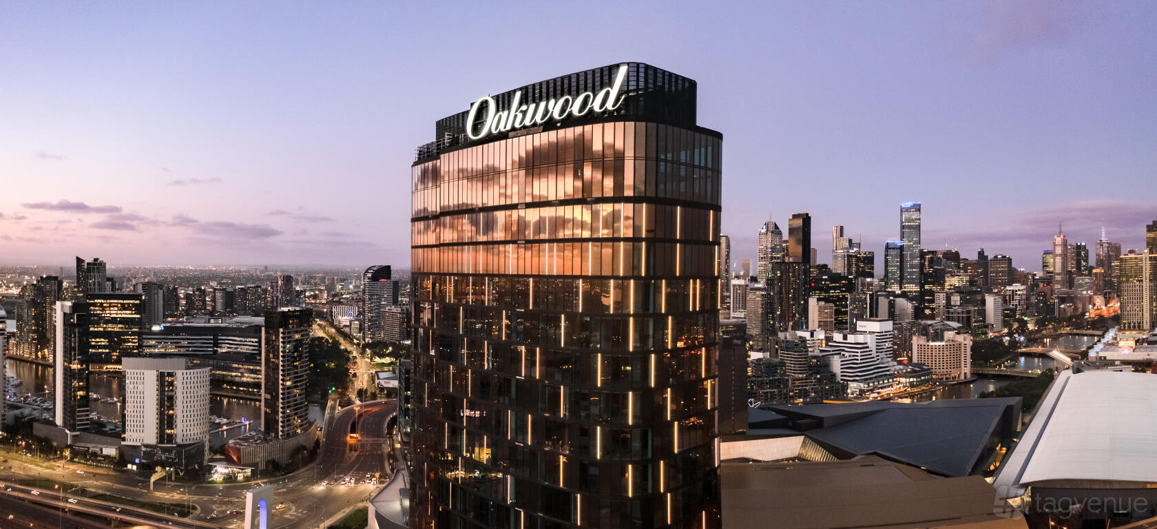 A high-rise hotel with glass exterior reflecting city lights at Oakwood Premier Melbourne.