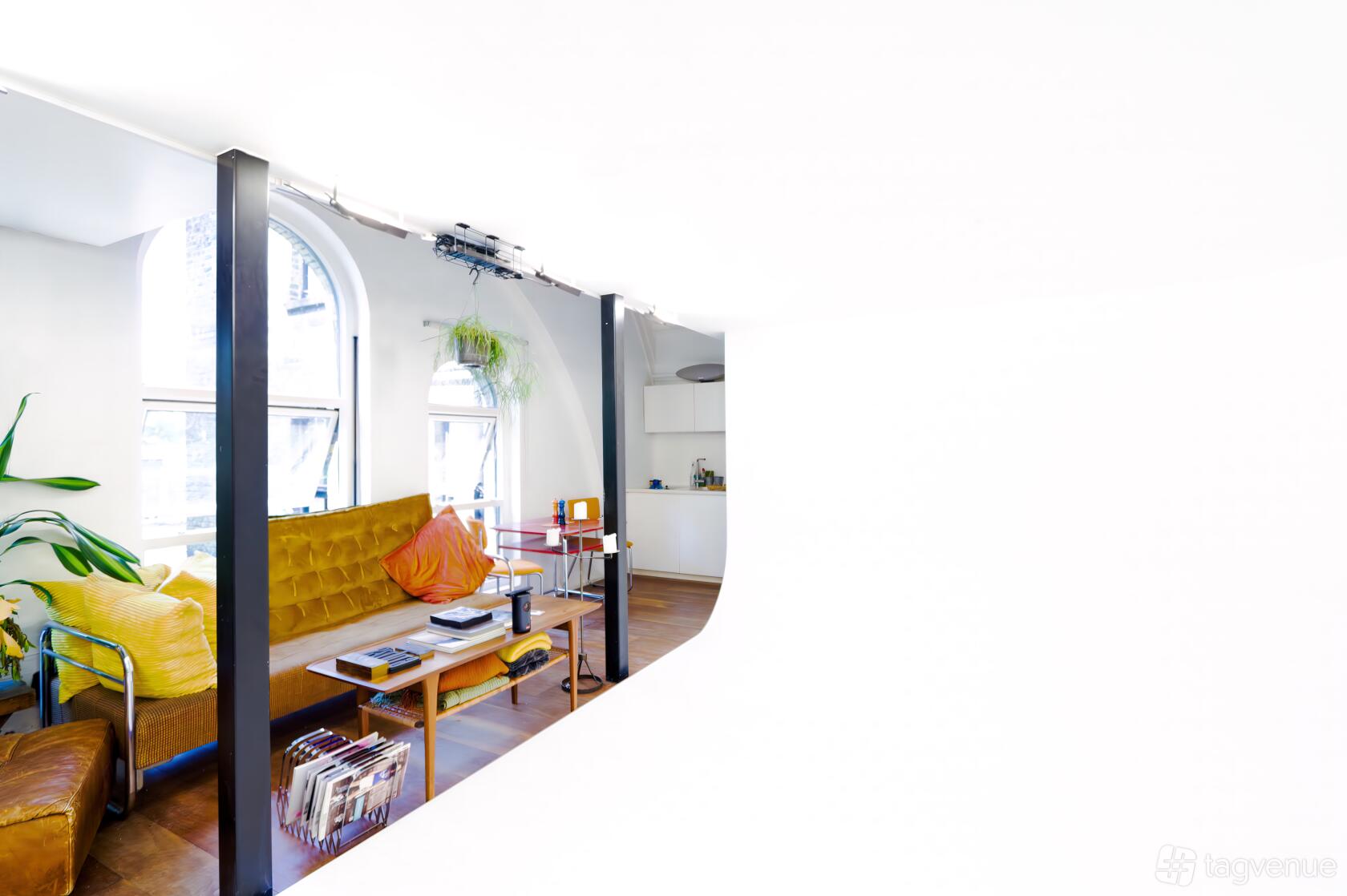 A photo studio with a curved white cyclorama, arched windows, and a lounge area at Client-facing Video & Photo Studio.