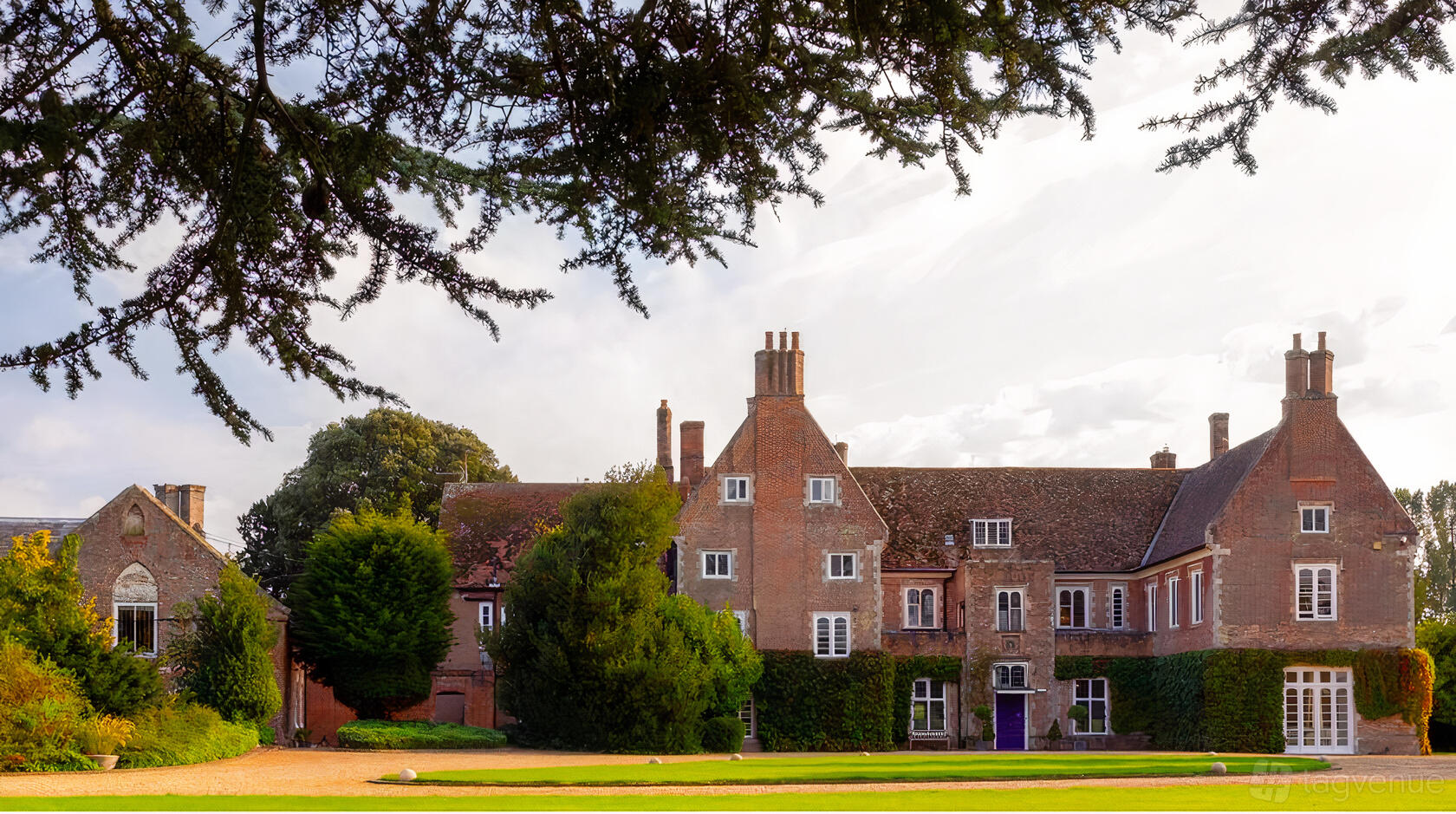 A historic country house with red brick exterior, tall chimneys, and ivy-covered walls at Hockwold Hall.