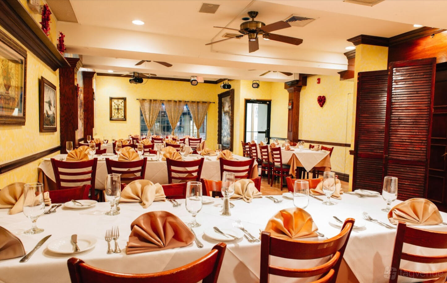 A restaurant dining room with white tablecloths, folded napkins, and wooden chairs at Piccolino Restaurant.