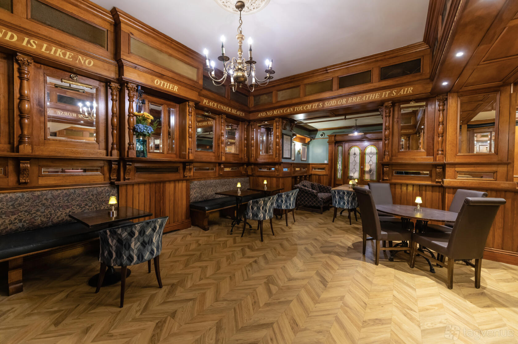 A cocktail bar with wood-paneled walls, upholstered seating, and chevron parquet floors at Harcourt Bar & Garden.