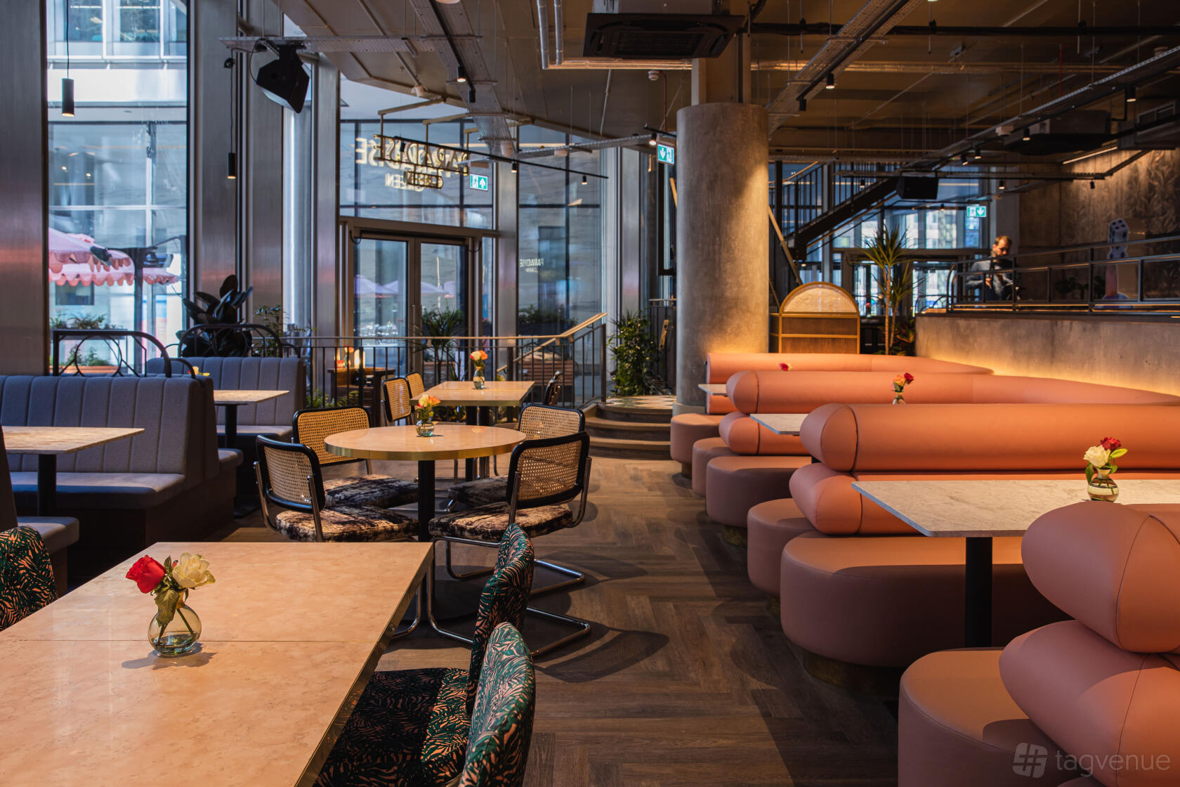 A restaurant with curved peach banquettes, round tables, and floor-to-ceiling windows at PARADISE GREEN, Bishopsgate.