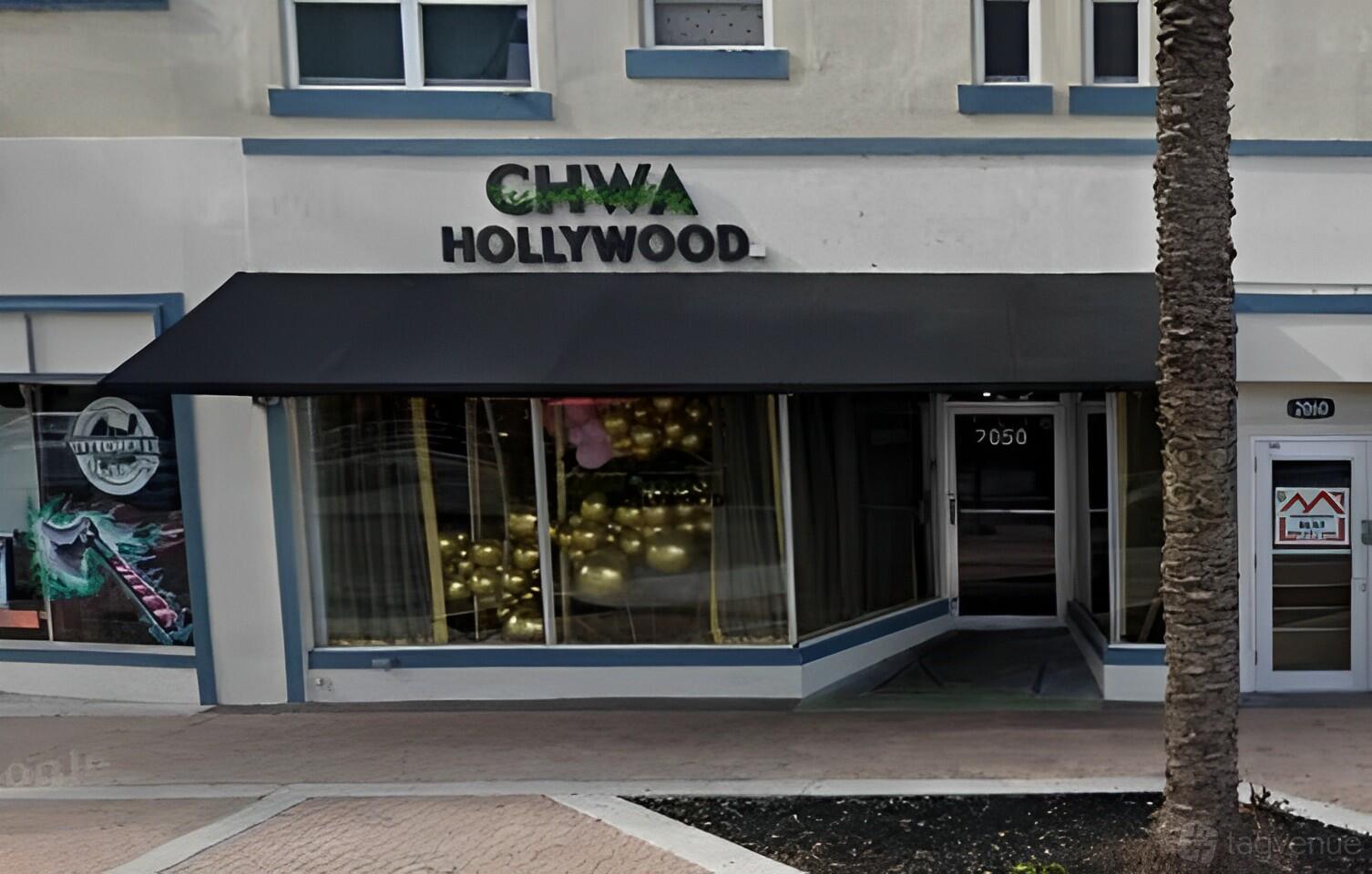 A restaurant exterior with a black awning, large front windows, and gold balloon decorations at Chwa Hollywood.