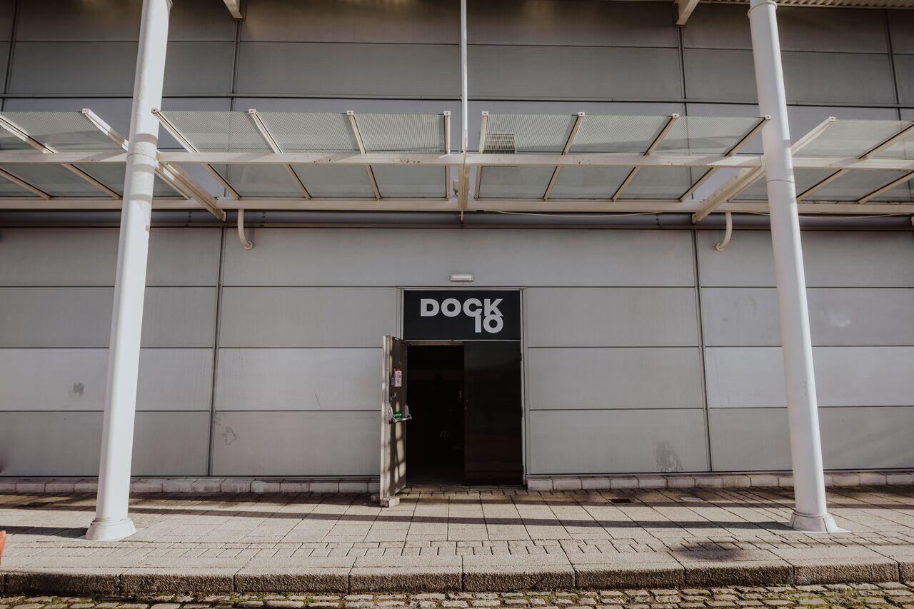 An industrial event venue with a glass canopy, large entryway, and Dock X London signage.