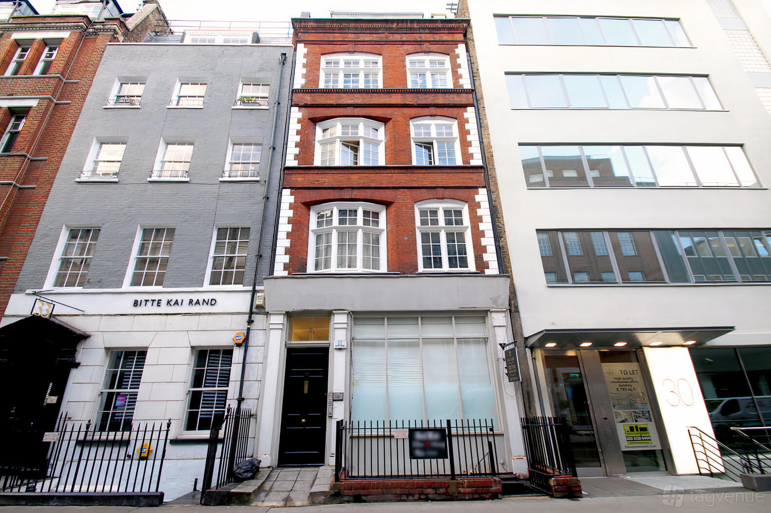 A gallery with a red brick facade, tall white-framed windows, and a street-level entrance at Grand Passion Pianos.