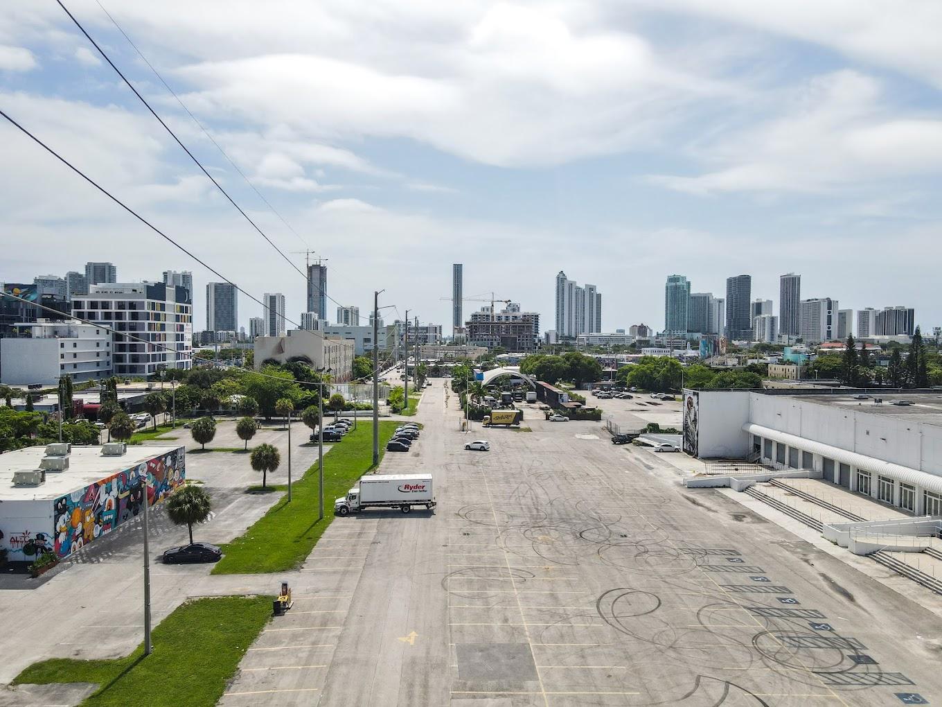 An outdoor space with a large open parking lot, city skyline views, and wall murals at Mana Wynwood Convention Center.