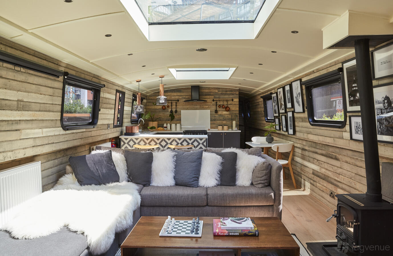 A hotel boat with skylights, wood-paneled walls, and a plush grey sofa in the main area at The Boathouse London - Paddington West.
