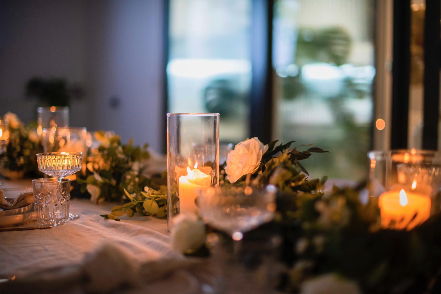An event venue with a long table set with candles, crystal glassware, and floral arrangements at Life+.