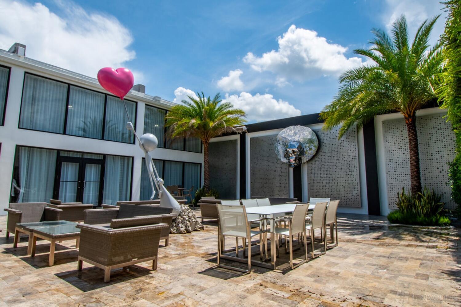 An event venue with contemporary outdoor seating, palm trees, and modern sculptures at Ikonick Collection.