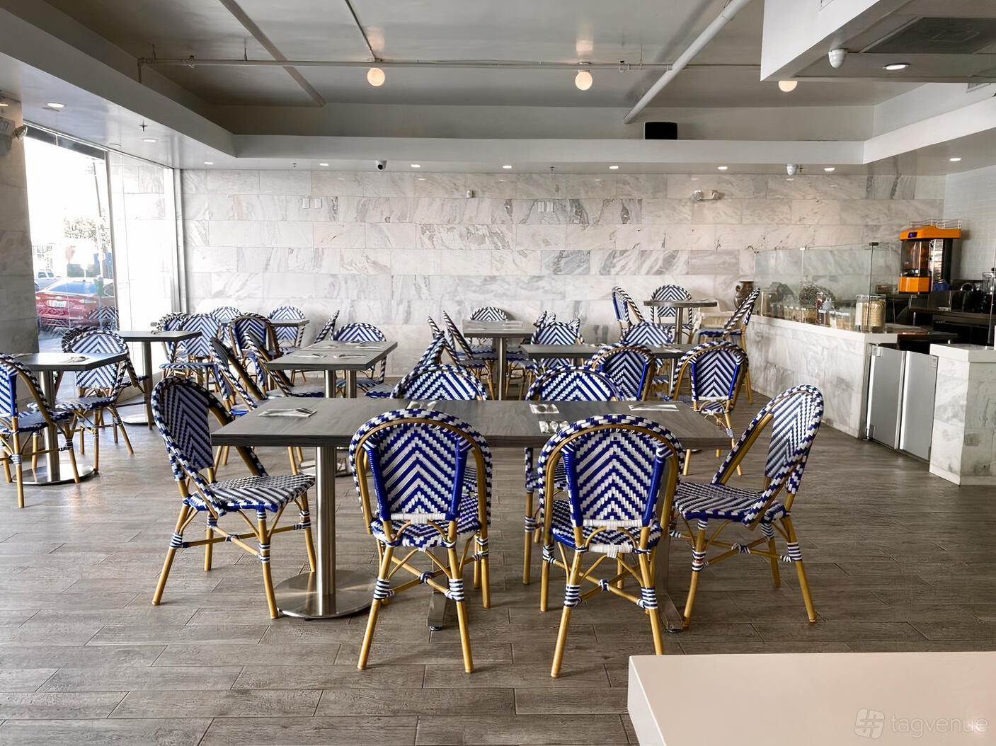 A restaurant with chevron-patterned blue chairs, marble walls, and floor-to-ceiling windows at Bombay Beach.