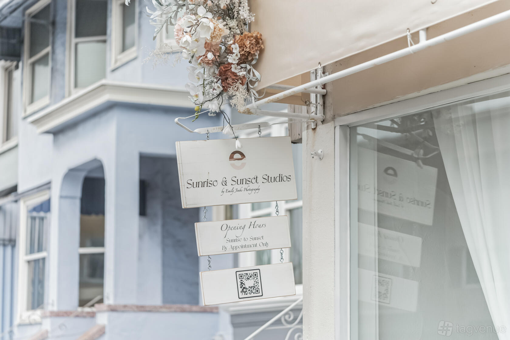 A film and photo studio with a hanging white sign decorated with dried flowers at Sunrise & Sunset Studios.