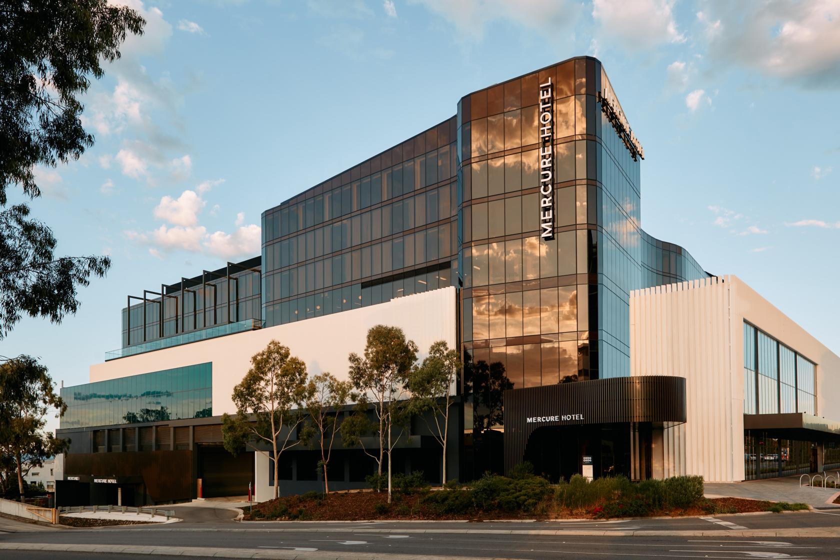 A hotel with glass facades, modern architecture, and landscaped surroundings at Mercure Melbourne Doncaster.
