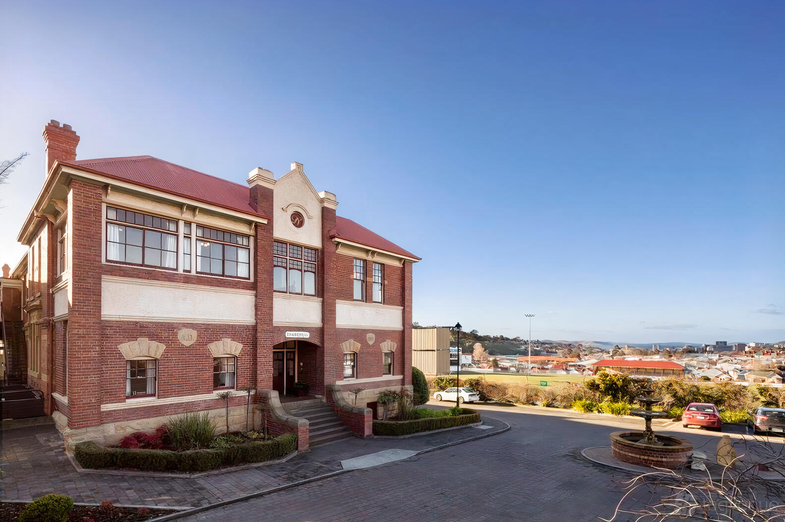 A heritage hotel with red brick facade, arched windows, and a circular driveway at Rydges Hobart.