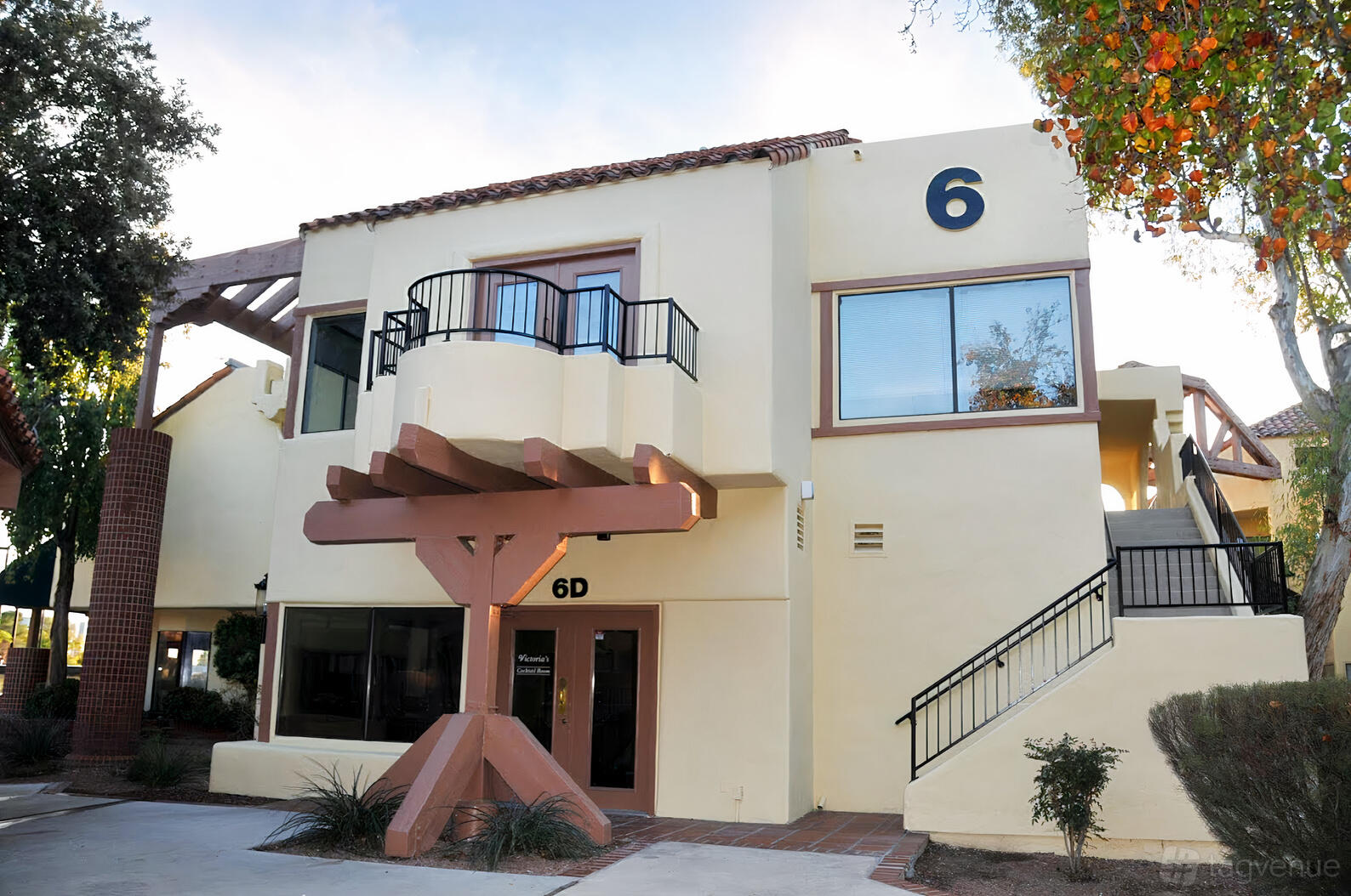 A conference centre with beige stucco exterior, black metal railings, and large windows at Hourly Meeting Room.
